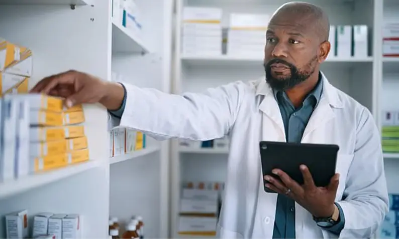 Pharmacist checking stock on a computer tablet