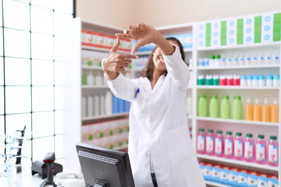 Female pharmacist behind counter making a square sign gesture